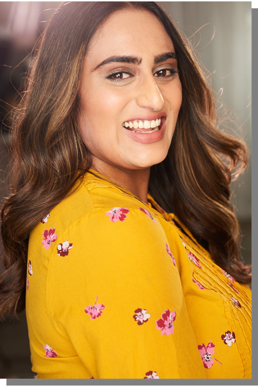 a person with long brown hair and a yellow blouse